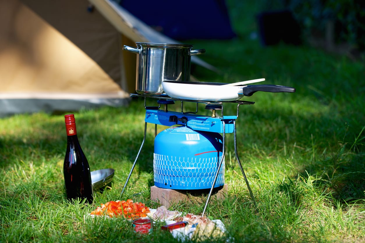 Family camping stove with gas canister and food on a camping trip