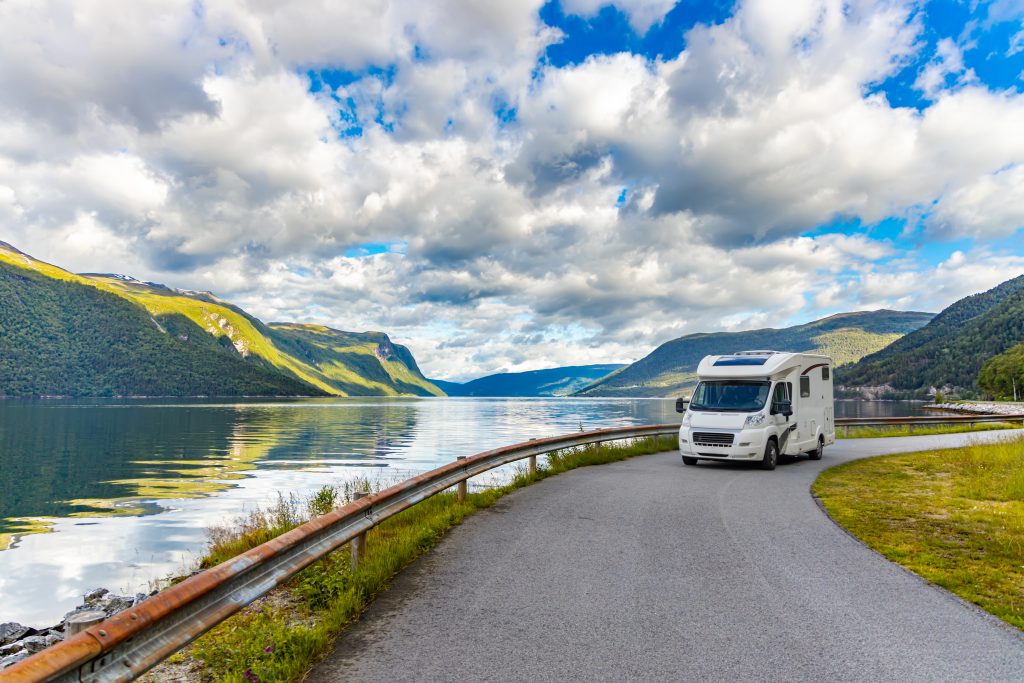 motor home driving across green landscape with water