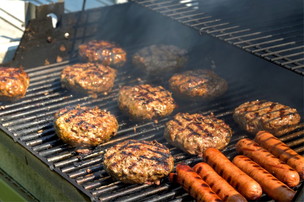 burgers and sausages cooking on a bbq
