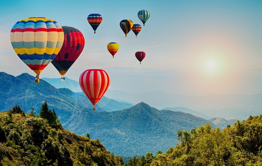 Hot air balloons flying over mountains