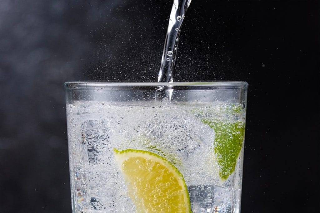 A fizzy drink with a mint leave and slice of lemon