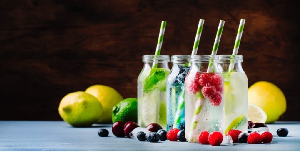 A group of bottles with straws and fruits