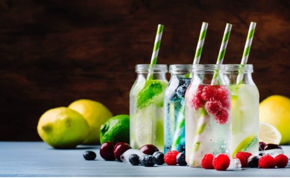 A group of bottles with straws and fruits