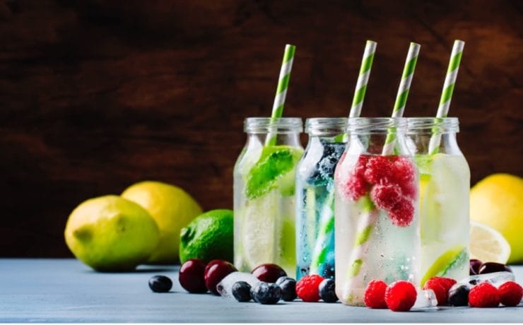 A group of bottles with straws and fruits