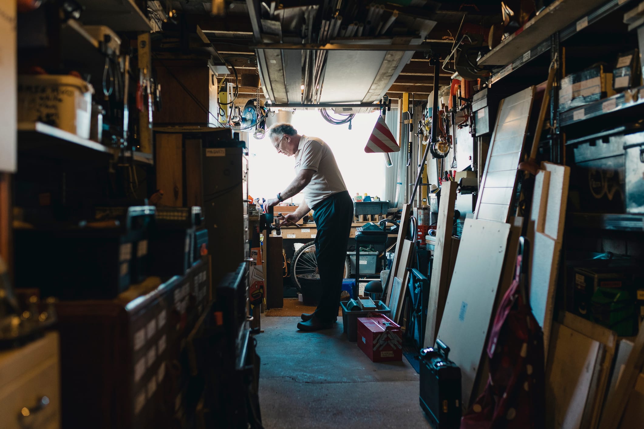 Senior man is working in his shed on a woodwork project. He is fatsening something in to a vice.